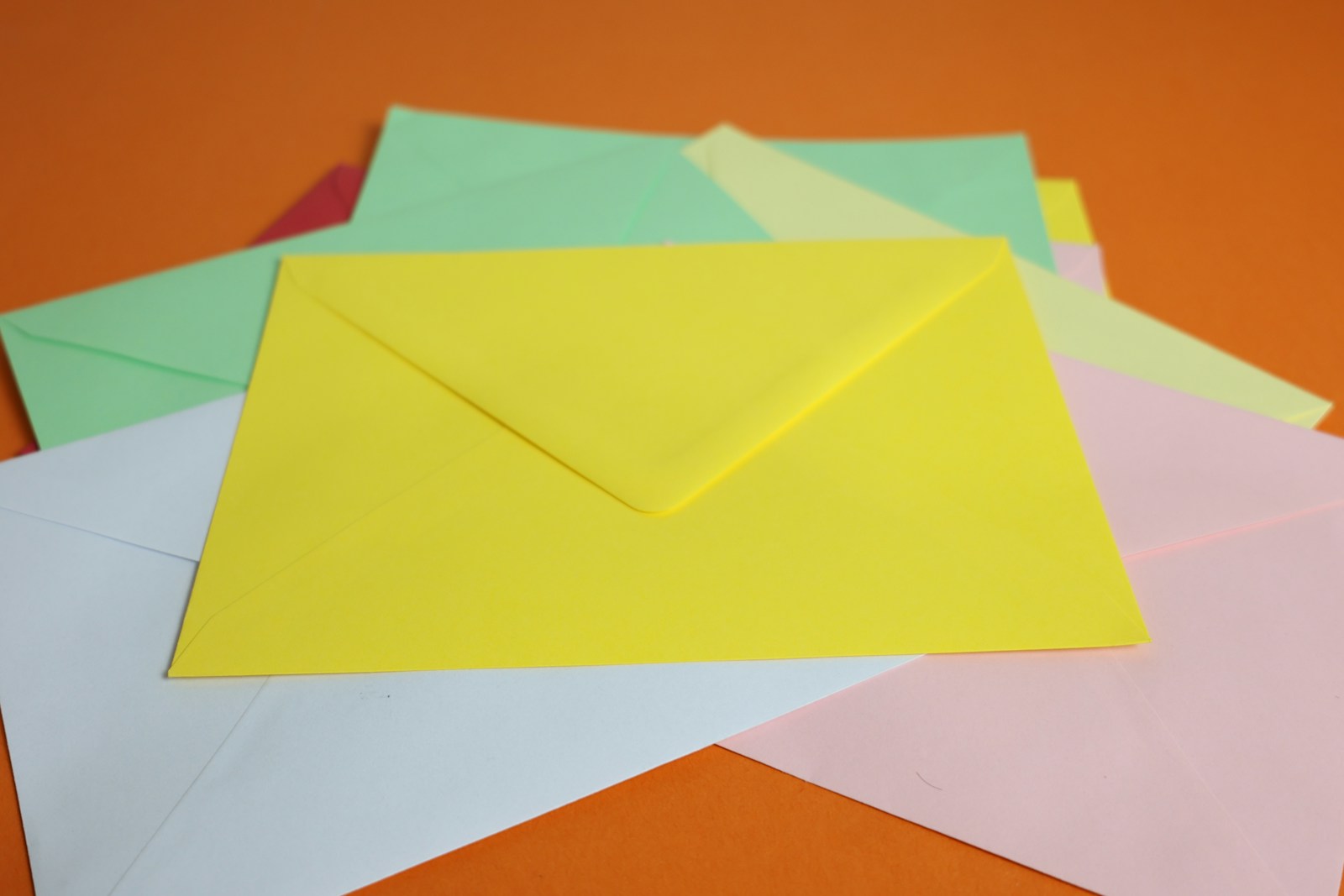 Colorful envelopes piled on an orange surface